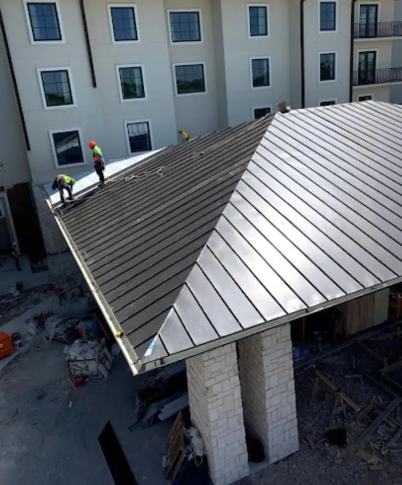 Crew installing standing seam metal roof panels on a commercial project in Lihue